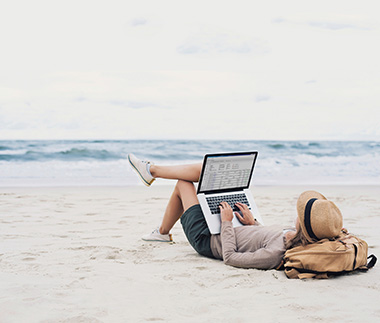 Mujer en la playa usando una laptop con CMS