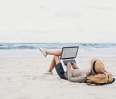 Mulher na praia usando laptop com CMS