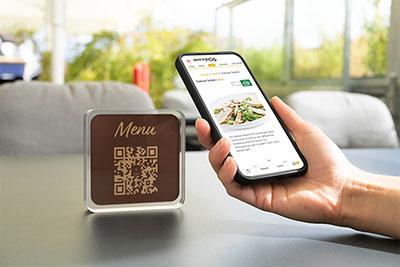 Teléfono móvil con tarjeta de menú, código QR en la mesa