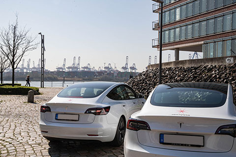 Zwei Tesla Autos mit OktoPOS Logo vor einem Bürogebäude